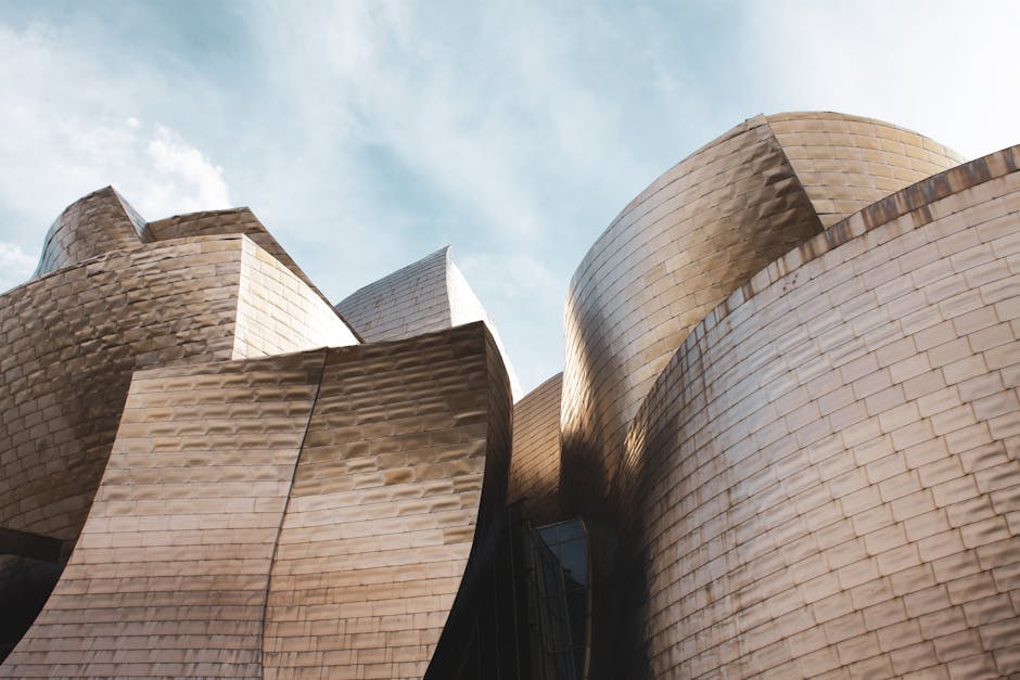 Low angle view of Guggenheim Museum Bilbao's modern architecture under a bright sky